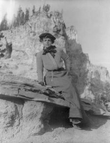 Frances Benjamin Johnston, full-length portrait, sitting on ledge with..., between 1888 and 1920. Creator: Frances Benjamin Johnston