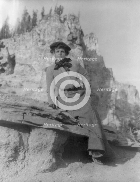 Frances Benjamin Johnston, full-length portrait, sitting on ledge with..., between 1888 and 1920. Creator: Frances Benjamin Johnston.
