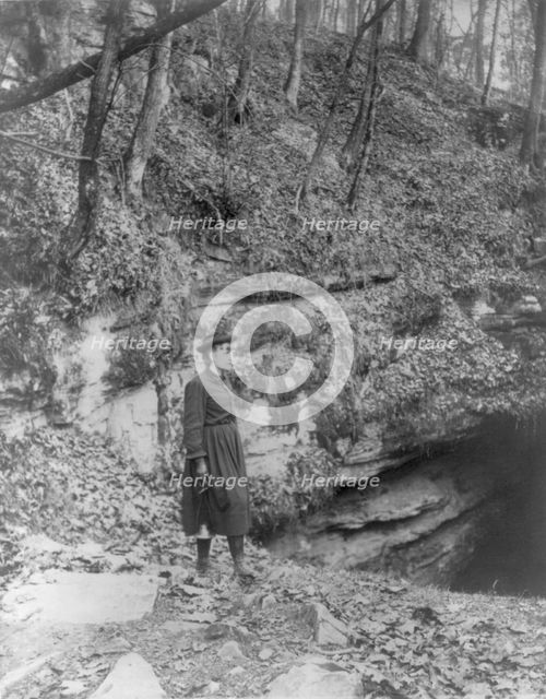 Frances Benjamin Johnston, full, standing by wooded cliff at entrance to Mammoth Cave, (c1891?). Creator: Frances Benjamin Johnston.