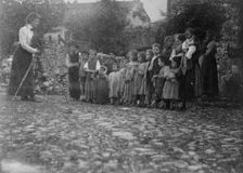 Frances Benjamin Johnston photographing a group of people, mostly children, in Europe, 1900. Creator: Unknown