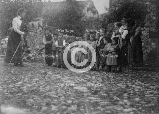 Frances Benjamin Johnston photographing a group of people, mostly children, in Europe, 1900. Creator: Unknown.