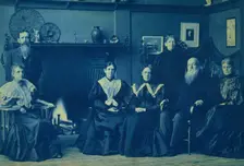 Frances Benjamin Johnston posed with six members of her family, by fireplace, in her Wash..., 1896. Creator: Frances Benjamin Johnston