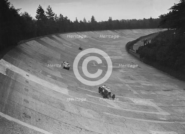 Frazer-Nash and Frazer-Nash BMW racing on the banking at Brooklands, 1938 or 1939. Artist: Bill Brunell.