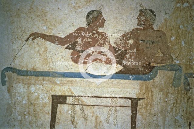 Fresco depicting two men lying on a bed in the Tuffatore tomb at Paestum.