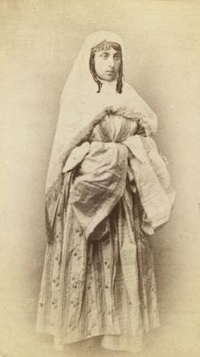 Full-length portrait of a woman, facing slightly right, in traditional dress, between 1870 and 1886. Creator: Unknown