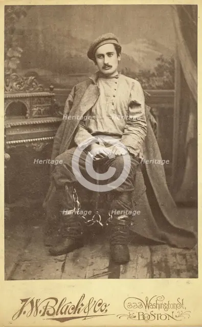 Full-length portrait of a man in convict clothing and leg irons, seated..., between 1880 and 1886. Creator: Unknown.