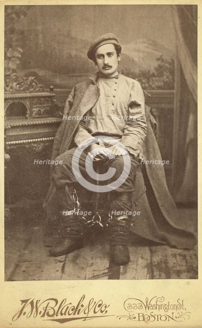 Full-length portrait of a man in convict clothing and leg irons, seated..., between 1880 and 1886. Creator: Unknown.