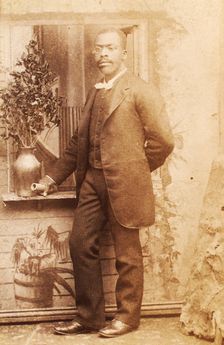 Full-length portrait of man, with studio props, c1880-c1889. Creator: Richmond Photograph Co