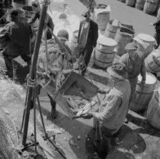 Fulton fish market stevedores unloading and weighing fish in the early morning, New York, 1943. Creator: Gordon Parks