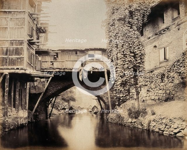 Kashmir: a built-over bridge on a canal betweeen houses, c1870s. Creator: Samuel Bourne.