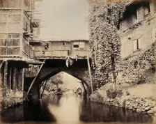 Kashmir: a built-over bridge on a canal betweeen houses, c1870s. Creator: Samuel Bourne
