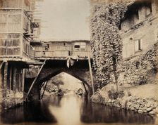 Kashmir: a built-over bridge on a canal betweeen houses, c1870s. Creator: Samuel Bourne
