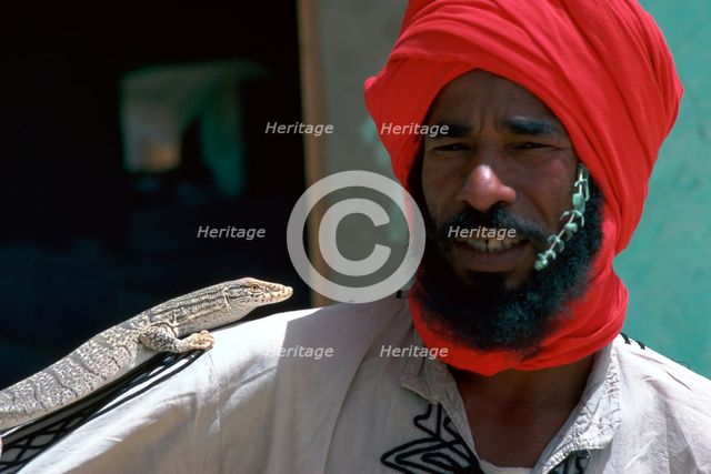 Keeper with a lizard in Tozeur zoo in Tunisia. Artist: Unknown