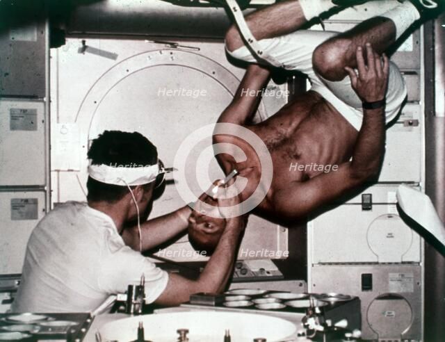 Kerwin examining Conrad on Skylab 2, 1973. Creator: NASA.