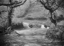 Kitty Brunell driving a 1930 Ford Model A 2-seater through a ford, 1931. Artist: Bill Brunell