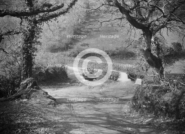 Kitty Brunell driving a 1930 Ford Model A 2-seater through a ford, 1931. Artist: Bill Brunell.