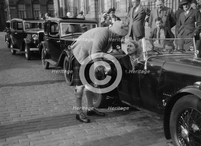 Kitty Brunell in her Aston Martin, chatting to a man in Highland dress, RSAC Scottish Rally, 1933. Artist: Bill Brunell.