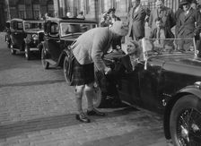 Kitty Brunell in her Aston Martin, chatting to a man in Highland dress, RSAC Scottish Rally, 1933. Artist: Bill Brunell