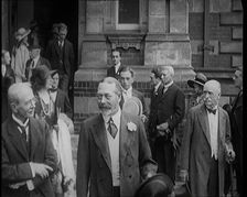 King George V Accompanied by a Group of Officials Emerging from a Building , 1924. Creator: British Pathe Ltd