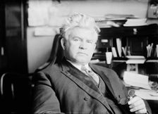 H.T. Rainey, holding bifocals, at desk, 1911. Creator: Bain News Service
