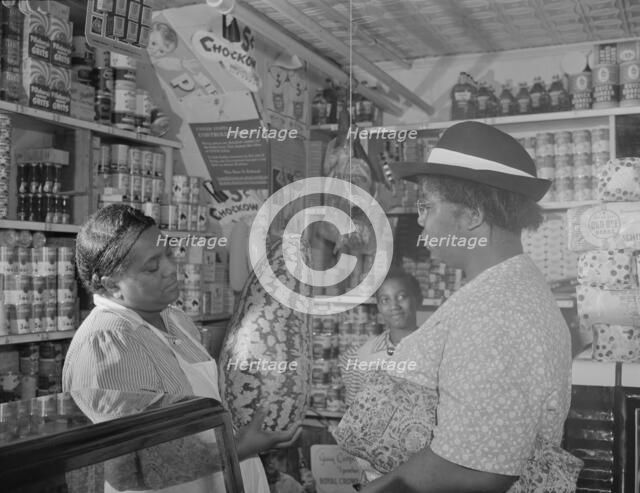 Housewife bargaining in the store owned by Mr. J. Benjamin, Washington, D.C., 1942. Creator: Gordon Parks.
