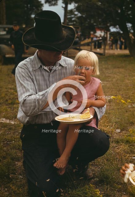 Homesteader feeding his daughter at the Pie Town, New Mexico Fair free barbeque, 1940. Creator: Russell Lee.