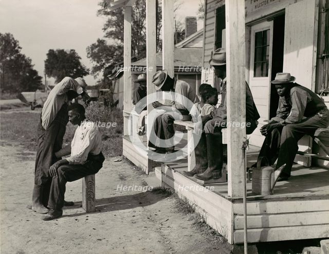 Haircutting in Front of General Store and Post Office on Marcella Plantation, Mileston, M..., 1939. Creator: Marion Post Wolcott.