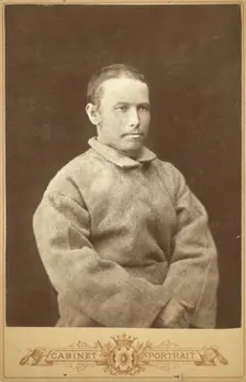 Half-length portrait of a man in convict coat, seated, facing right, between 1880 and 1886. Creator: Unknown