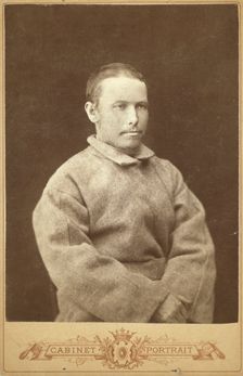 Half-length portrait of a man in convict coat, seated, facing right, between 1880 and 1886. Creator: Unknown