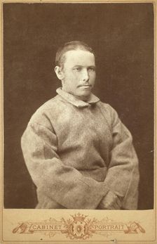 Half-length portrait of a man in convict coat, seated, facing right, between 1880 and 1886. Creator: Unknown