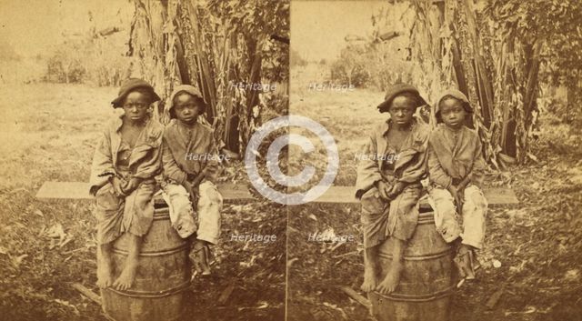 Happy little nig's, [Two boys sitting on a barrel in a field], (1868-1900?). Creator: Unknown.