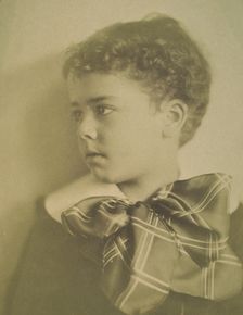 Head-and-shoulders portrait of a young boy with a large plaid bow at the neck of his..., c1900. Creator: Horace L Bundy