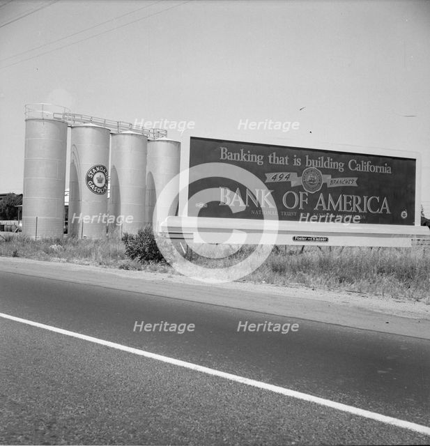 Highway gas tanks and signboard approaching town, between Tulare and Fresno on U.S. 99, 1939. Creator: Dorothea Lange.