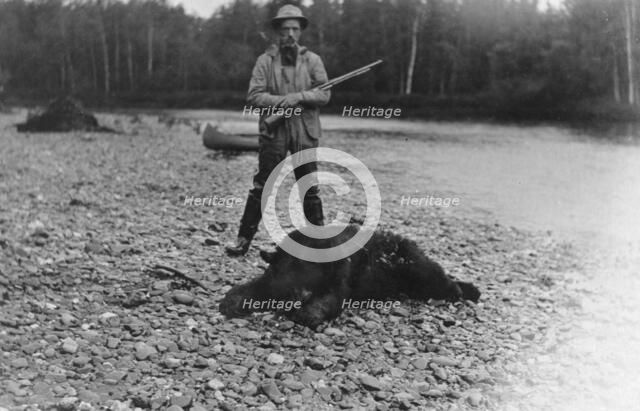 Hunter with bear which he killed, between c1900 and 1927. Creator: Unknown.