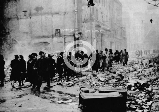 'In the morning, work as usual. After a big raid, the way to the office is knee-deep in rubble. Lond Artist: Unknown.