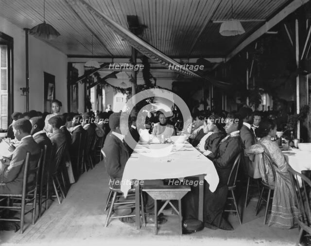Interior view of dining hall, decorated for the holidays, with students... Tuskegee Institute, c1902 Creator: Frances Benjamin Johnston.