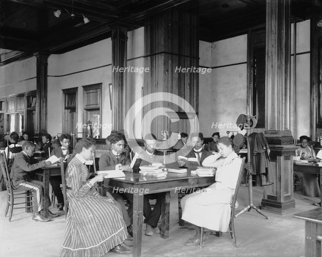 Interior view of library reading room with male and female students... Tuskegee Institute, c1902. Creator: Frances Benjamin Johnston.