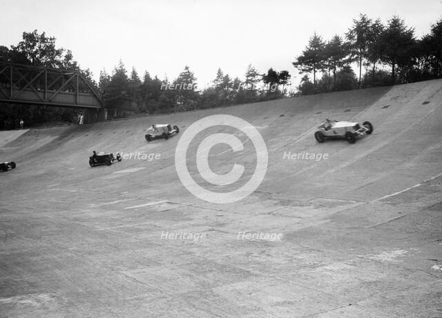 Invicta, Talbot and Frazer-Nash cars racing on the Members Banking at Brooklands. Artist: Bill Brunell.