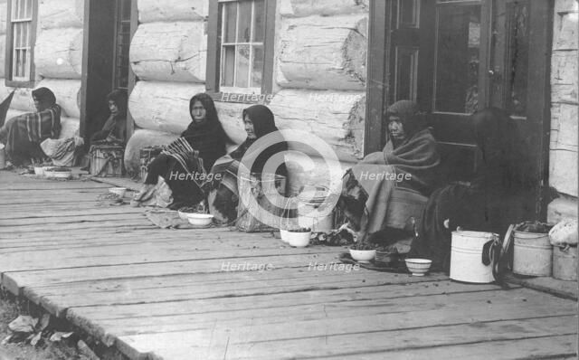 Indians sitting with backs to wall selling berries, between c1900 and c1930. Creator: Unknown.