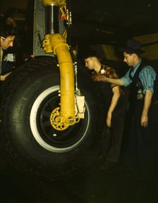 Inspecting of landing wheel of the transport planes at Willow Run, between 1941 and 1945. Creator: Howard Hollem