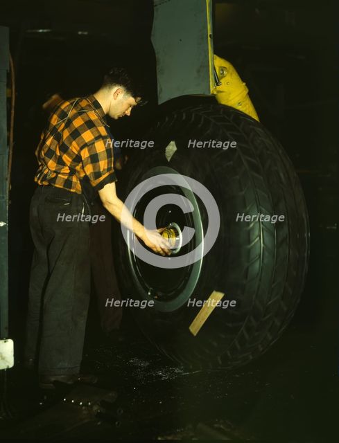 Inspecting of landing wheel of the transport planes at Willow Run, between 1941 and 1945. Creator: Howard Hollem.
