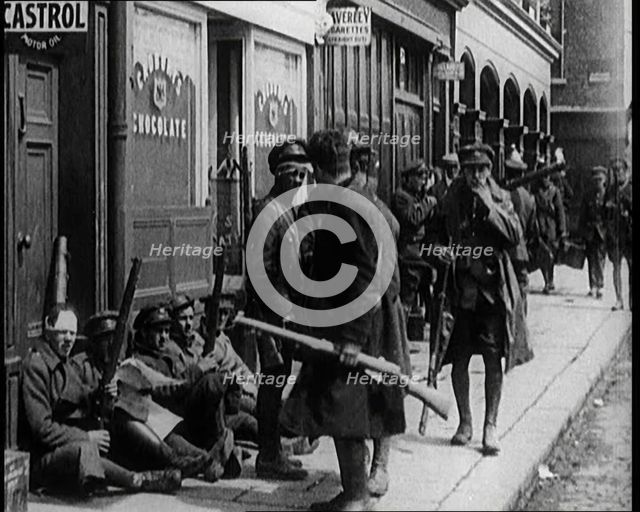 Irish Soldiers Sitting in the Street and Tending to Their Injuries from Fighting in Dublin, 1922. Creator: British Pathe Ltd.