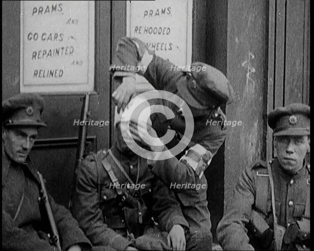 Irish Soldiers Sitting in the Street and Tending to Their Injuries from Fighting in Dublin, 1922. Creator: British Pathe Ltd.