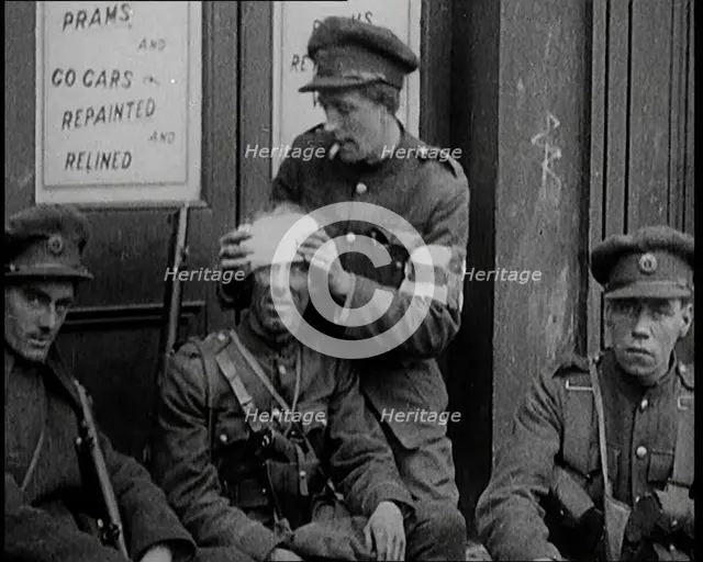 Irish Soldiers Sitting in the Street and Tending to Their Injuries from Fighting in Dublin, 1922. Creator: British Pathe Ltd.