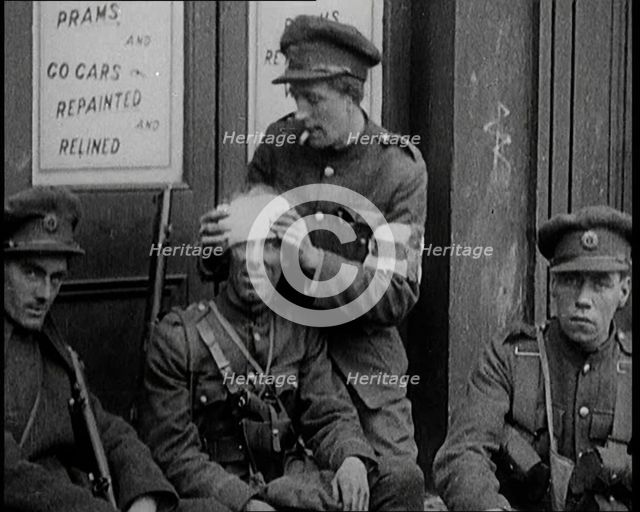 Irish Soldiers Sitting in the Street and Tending to Their Injuries from Fighting in Dublin, 1922. Creator: British Pathe Ltd.