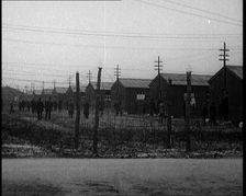 Irish Prisoners Walking Across a Barbed Wire Fenced Prison Ground, 1921. Creator: British Pathe Ltd