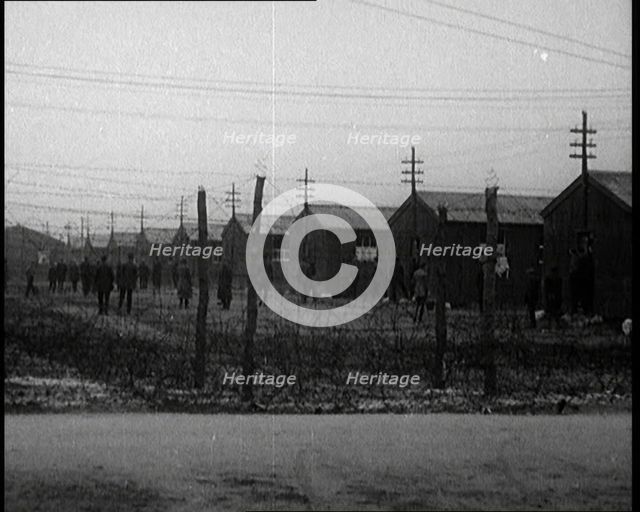 Irish Prisoners Walking Across a Barbed Wire Fenced Prison Ground, 1921. Creator: British Pathe Ltd.