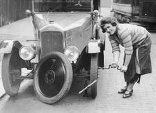 Ivy Cummings changing a tyre on a 1925 Singer 10/26, London, c1925