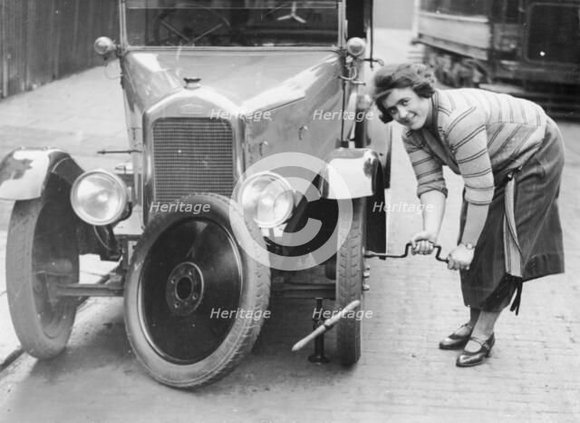 Ivy Cummings changing a tyre on a 1925 Singer 10/26, London, c1925. Artist: Unknown