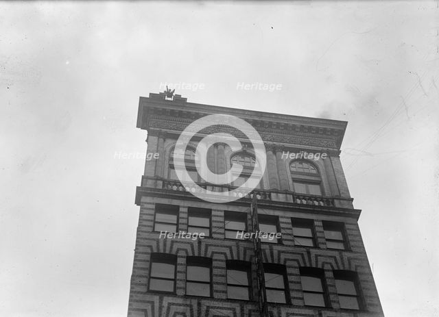 J. Reynolds, Performing Acrobatic And Balancing Acts On High Cornice Above 9th Street, N.W., 1917. Creator: Harris & Ewing.